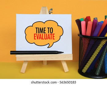 TIME TO EVALUATE - Concept of text at canvas with stand and basket pen on wooden table
