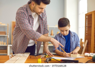 Time For Family. Father Teaching Son To Build Wooden House Using Hand Tools And Wooden Plank At Home Carpentry And Joinery Workshop. Dad And Boy Child Working Together Make Toy For School DIY Project