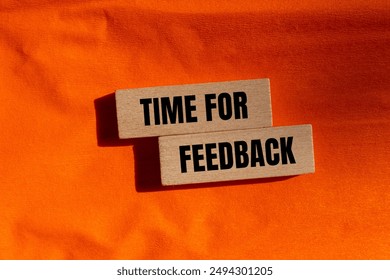 Time for feedback message written on wooden blocks with orange background. Conceptual time for feedback symbol. Copy space.