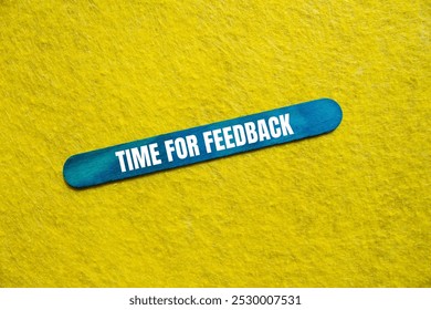 Time for feedback message written on blue wooden stick with yellow background. Conceptual time for feedback symbol. Copy space.