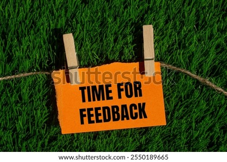 Time for feedback message written on ripped torn orange paper piece with green grass background. Conceptual time for feedback symbol. Copy space.