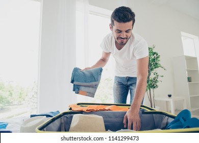 Time to fly for the holidays! Happy and joyful young man packing jeans in a suitcase - Powered by Shutterstock