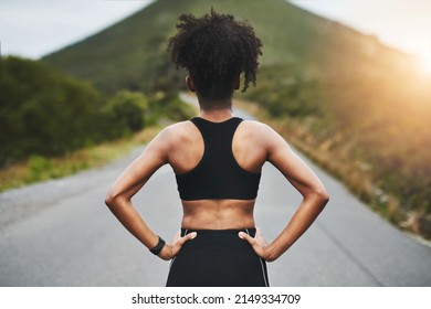 Time To Get Back On Track. Rearview Shot Of An Unrecognizable Young Sportswoman Standing With Her Hands On Her Hips Outside.