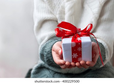 time gifts. gift box with a red ribbon in the hands of a little girl