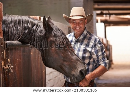 Its time to go for a ride. A caring ranch hand attending to a horse in the stable.