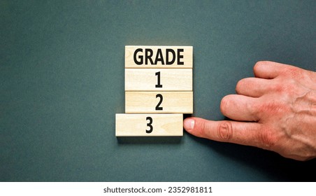 Time to grade 3 symbol. Concept word Grade 1 2 3 on wooden block. Businessman hand. Beautiful grey table grey background. Business planning and time to grade 3 concept. Copy space. - Shutterstock ID 2352981811