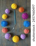 Time for hobby, concept. Colorful balls of wool and сrochet hooks like clock. Dark rustic table