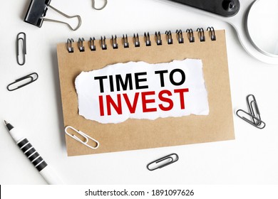 time to invest, text on white notepad paper, on a WHITE background. near the magnifier, pens of stationery clips - Shutterstock ID 1891097626