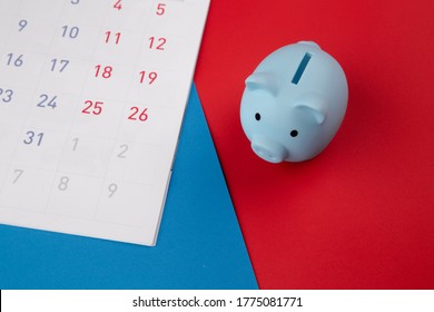 Time to invest,business concept. Blue piggy bank with calendar on colorful background. Top view