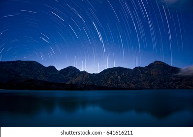 A time lapse exposure showing star trails over the crater lake at Mount Rinjani, Indonesia's second largest active volcano. Astrophotography at the segara anak at Gunung Rinjani, Lombok, Indonesia.