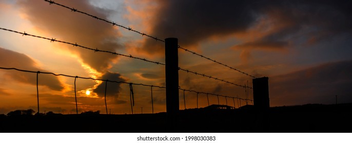 Time Lapse Sunset With Clouds Over The Barbed Wire Fence.