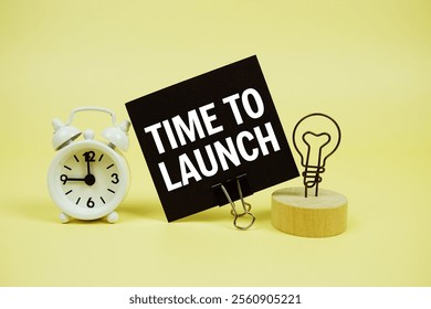 Time To Launch text message on paper card with alarm clcok on yellow background