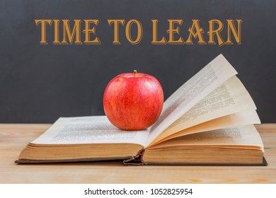 Time to learn. open book & red apple on school blackboard background