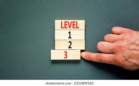Time to level 3 symbol. Concept word Level 1 2 3 on wooden block. Businessman hand. Beautiful grey table grey background. Business planning and time to level 3 concept. Copy space.