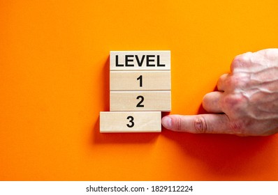 Time to level 3. Wooden blocks form the words 'level, 1, 2, 3,' on orange background. Male hand. Beautiful background. Business concept.
