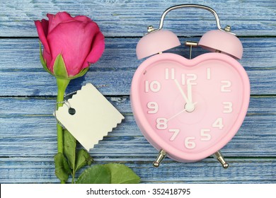 Time of love. pink rose, greeting card and pink heart watch on the blue wooden background for valentine day.