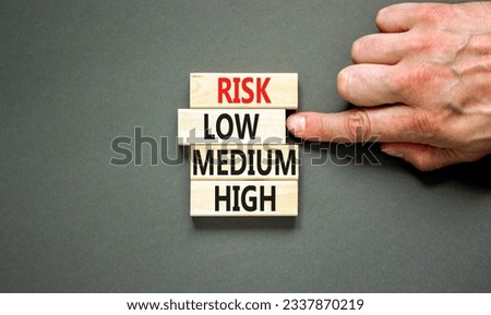 Time to low risk symbol. Concept word Risk low medium high on wooden block. Businessman hand. Beautiful grey table grey background. Business time to low risk concept. Copy space.