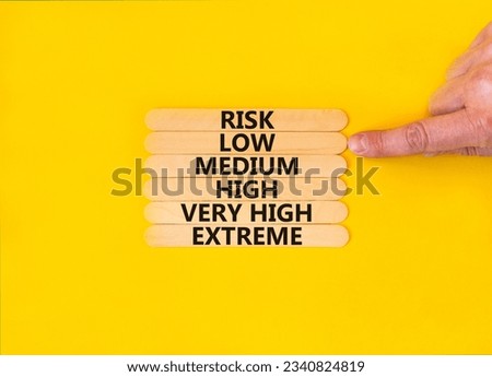 Time to low risk symbol. Concept word Risk low medium high very high extreme on wooden sticks. Businessman hand. Beautiful yellow background. Business time to low risk concept. Copy space.