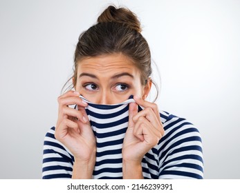 Time To Make Like A Tortoise And Hide. Shot Of A Beautiful Young Woman Using Her Shirt To Cover Her Mouth And Nose.