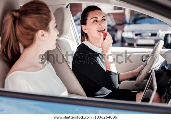 Time to make up. Stylish\
fashionable cute woman sitting in the car looking in mirror and\
sprucing.