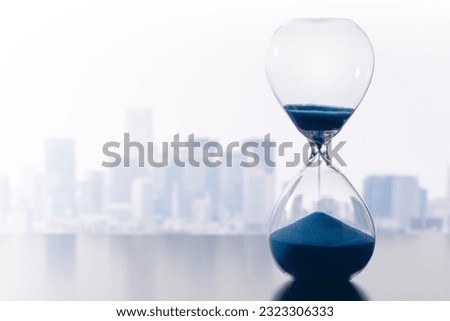 Time management in business. Blue sand timer and cityscape.