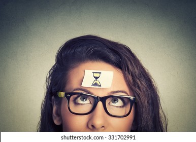 Time management concept young woman with sand clock sign sticker on her forehead 