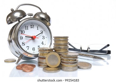 Time is money - Alarm clock, glasses, ball pen and piles of money coins on white background
