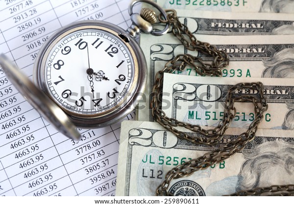 Time is money. Closeup of dollar\
bank notes near open pocket watch on paper list with\
digits