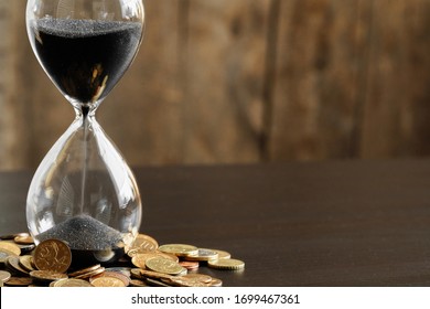 Time is money concept. Close up of hourglass with money coins