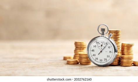 Time is money. Stopwatch and stacks of coins on a wooden background. Template Copy space for text.
