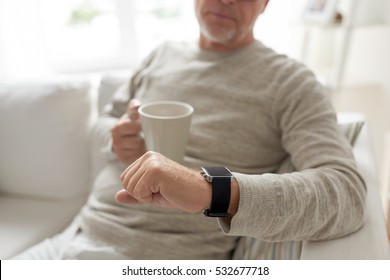 time, morning and people concept - close up of senior man with coffee or tea mug looking at wristwatch at home - Powered by Shutterstock