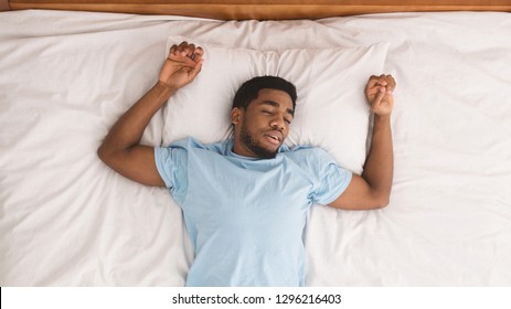 Time to nap. Black millennial guy sleeping in bed, top view