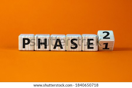 Time for Phase 2. Turntd a cube and changed the word 'Phase 1' to 'Phase 2'. Beautiful orange background. Business concept. Copy space.