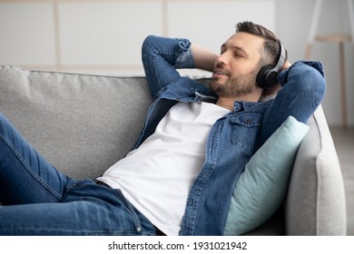 Time To Relax. Handsome Middle-aged Bearded Man In Wireless Headphones Listening To Music, Copy Space, Closeup. Happy Man In Headset With Eyes Closed Relaxing On Couch In Living Room