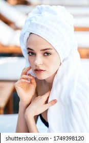 Time To Relax. Portrait Of A Young Beautiful Caucasian Woman With White Hair Towel Wrap Looking At Camera With Her Piercing Brown Eyes While Sitting In Spa Environment. Beauty Concept. Vertical Shot