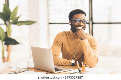 Time To Relax. Satisfied afro man in headphones listening to music in office, looking aside, free space - Powered by Shutterstock