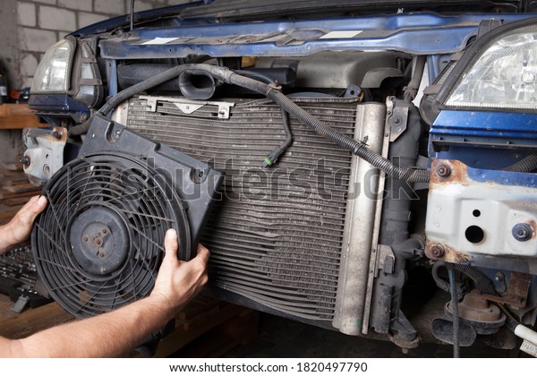 It\'s time to replace a corroded car radiator.\
Removing the radiator from the\
car