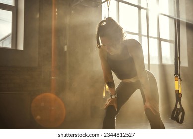 Time to rest. Young athletic woman in sportswear looking exhausted while standing in front of windows at gym. - Powered by Shutterstock