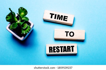 TIME TO RESTART Is Written On Wooden Blocks On A Light Blue Background Near A Flower In A Pot