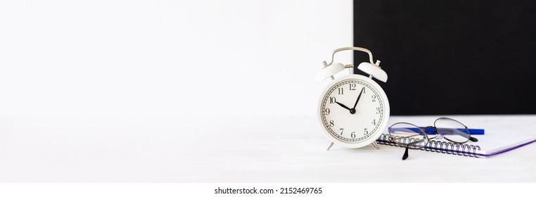 Time To Return Back To School Or Back To The Office. White Alarm Clock, Stationery. Glasses, Black Board. Banner, Copy Space For Text, White Background