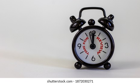 Time to review concept. Beautiful black alarm clock with words 'time to review'. White table. Beautiful white background. Copy space. Business and time to review concept.