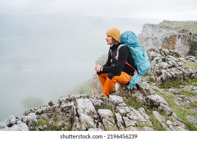 Time For Solitude, Alone In The Mountains, A Guy Traveling Alone, Mountain Climbing, A Man Sitting On A Rock In The Mountains, Resting On A Halt On A Hike. High Quality Photo