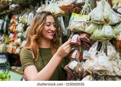 Time To Spice Up Your Life. Shot Of A Cheerful Young Woman Holding A Bag Of Spice While Browsing Through The Selection At A Market Stall Outside.