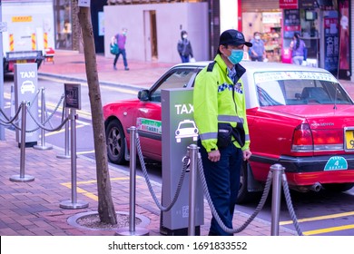 Time Square/Hong Kong - Apr 3 2020: Mask-wearing Security Worker Standing Beside A Line Of Taxis 