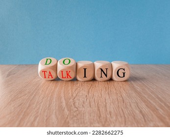 Time to start doing. Turned cubes and changes the word 'talking' to 'doing'. Beautiful blue background, wooden table Business, motivational and start doing concept. Copy space.