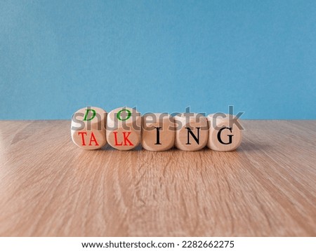 Time to start doing. Turned cubes and changes the word 'talking' to 'doing'. Beautiful blue background, wooden table Business, motivational and start doing concept. Copy space.