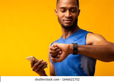 Time To Start. Portrait of black muscular man looking at smartwatch, holding smartphone, checking fitness tracker - Powered by Shutterstock