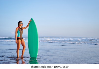 It's time for surfing! Hobby and vacation. Pretty young woman holding surf board on the sea beach. - Powered by Shutterstock