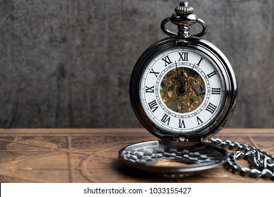 Time symbol or business deadline countdown concept, closed up vintage pocket watch on brown old book with black dark cement wall. - Powered by Shutterstock