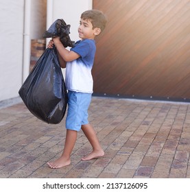 Time To Take Out The Trash. Shot Of A Little Boy Taking Out The Trash At Home.